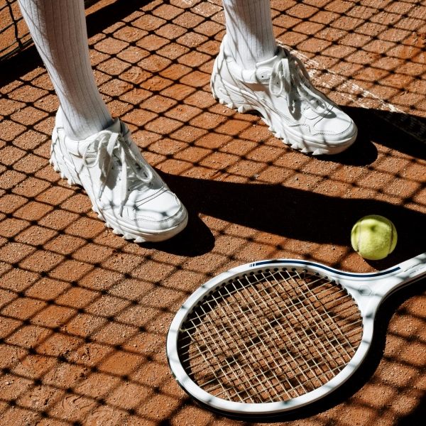 Person Wearing White compression socks Beside a Tennis Racket