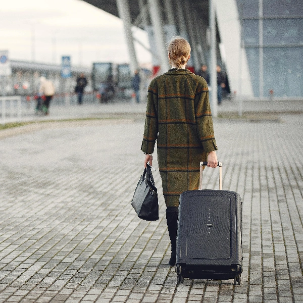 woman with suitcase walking near airport terminal