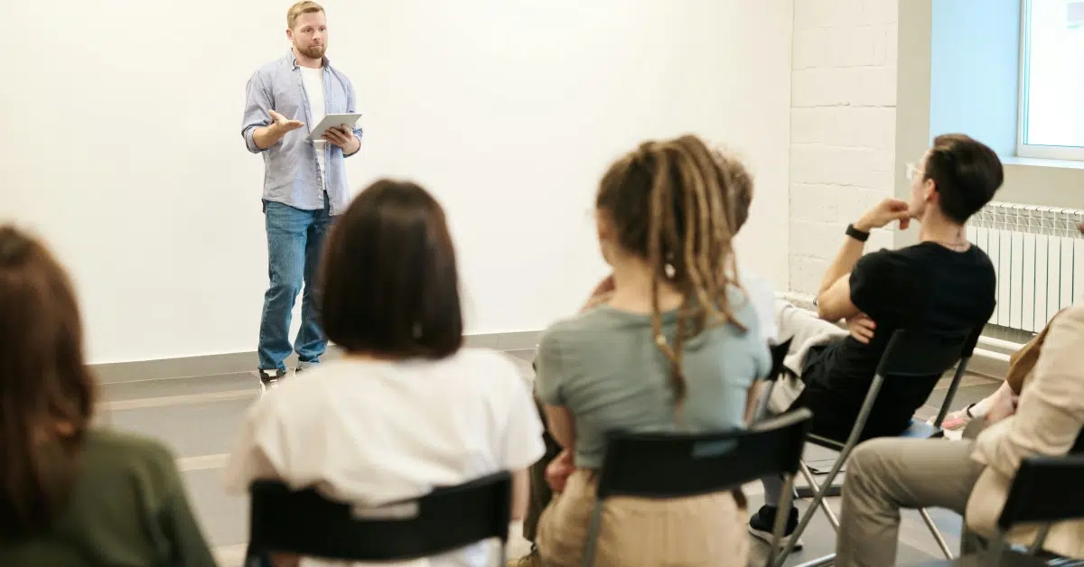 A man Speaking with Gray Dress Shirt and Blue Jeans