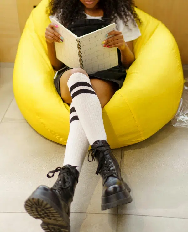 A Girl Reading a White Notebook with Compression Socks.
